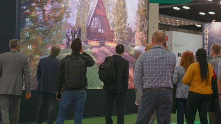 A crowd views an LED wall showing themselves in front of a cabin in the forest.